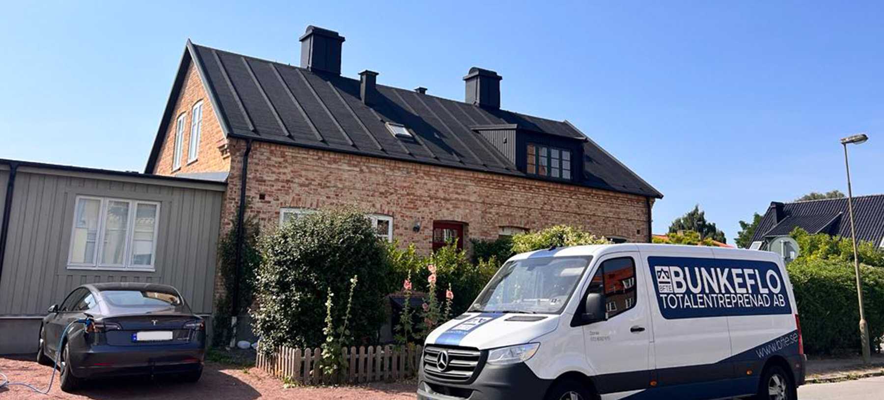Hus med svart listtäckning, längre ifrån. 