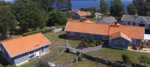 Vittinge tegeltak på stort ljusblått hus i Onsala, havet syns i bakgrunden.
