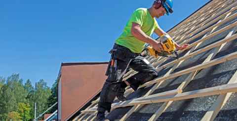 Tagläggare som skruvar på läkten på taket.